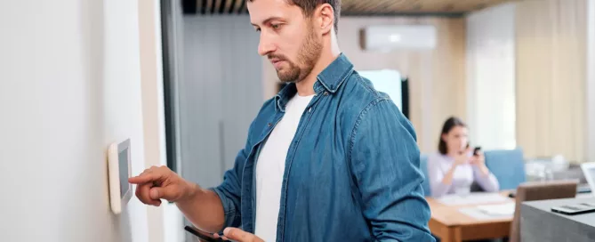 Man changing electronic thermostat settings