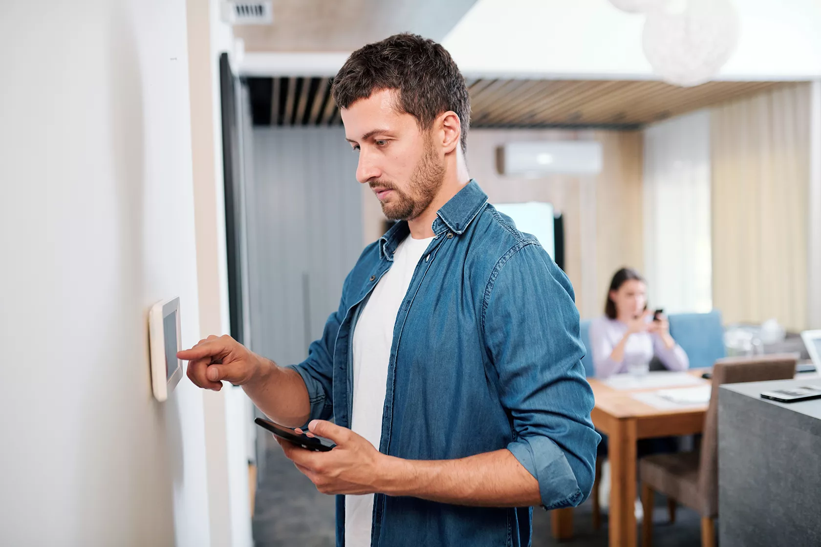Man changing electronic thermostat settings